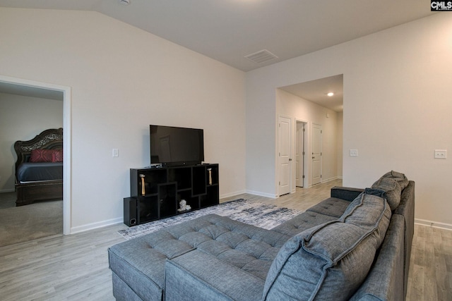 living area with lofted ceiling, light wood-style flooring, visible vents, and baseboards