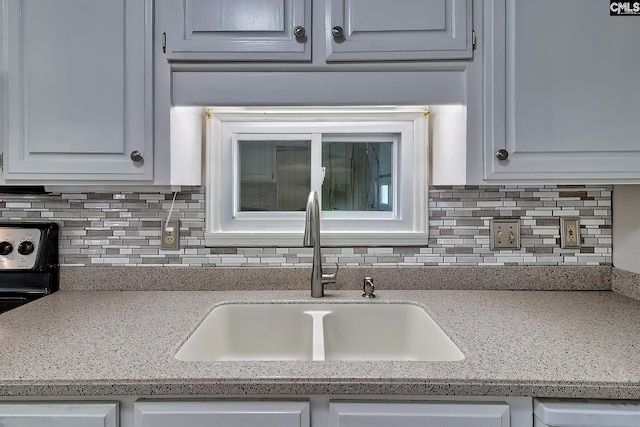 kitchen featuring light countertops, backsplash, and a sink