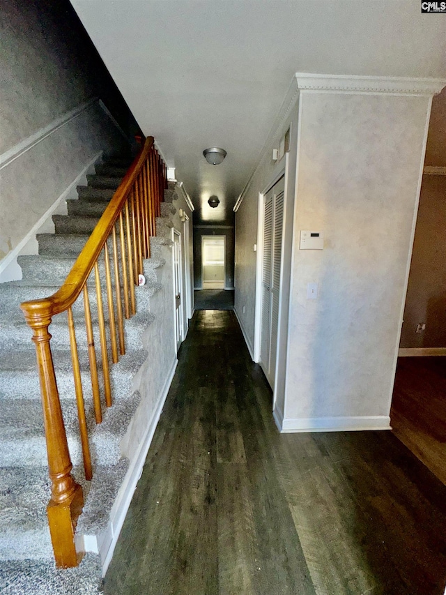 corridor with stairway, wood finished floors, baseboards, and ornamental molding