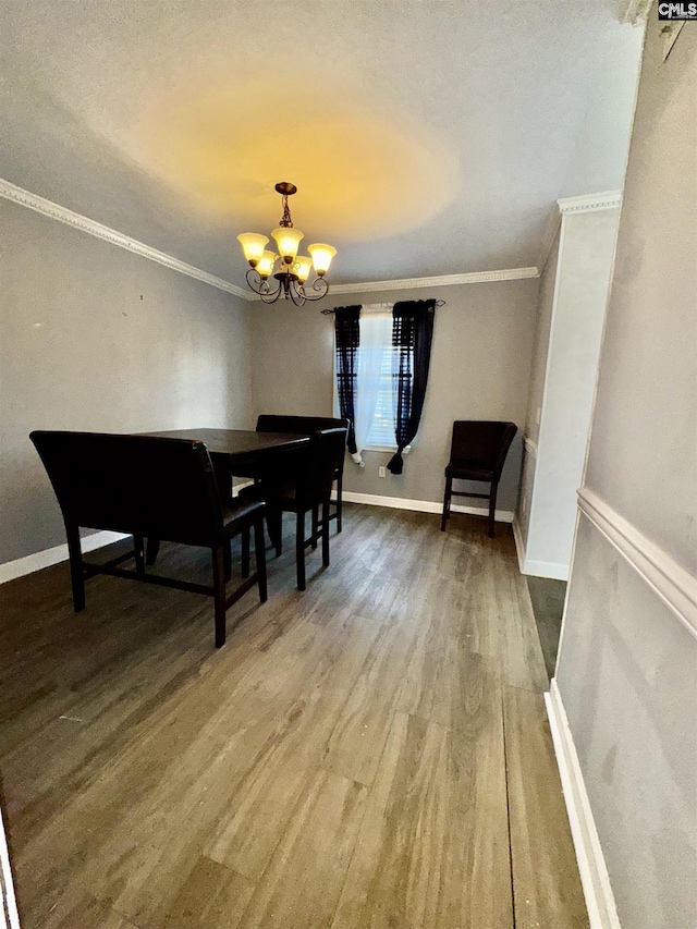 dining area featuring a chandelier, crown molding, baseboards, and wood finished floors