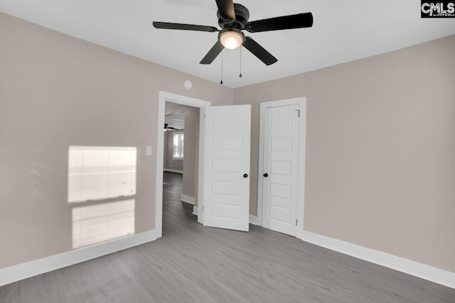 unfurnished bedroom with a ceiling fan, wood finished floors, and baseboards