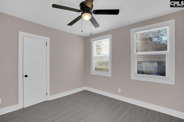 empty room featuring dark wood finished floors, a ceiling fan, and baseboards