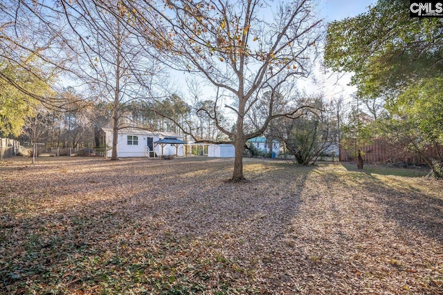 view of yard featuring an outbuilding, a storage shed, and fence