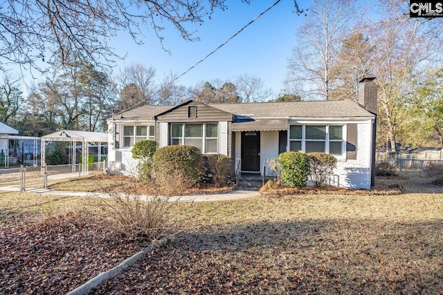 view of front of house with a gate, fence, brick siding, and a chimney