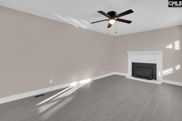 unfurnished living room with visible vents, ceiling fan, baseboards, a fireplace, and wood finished floors