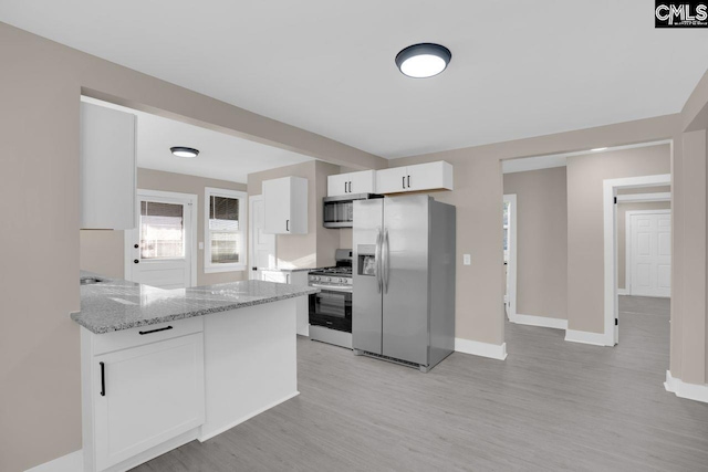 kitchen with stainless steel appliances, baseboards, white cabinets, light wood finished floors, and light stone countertops