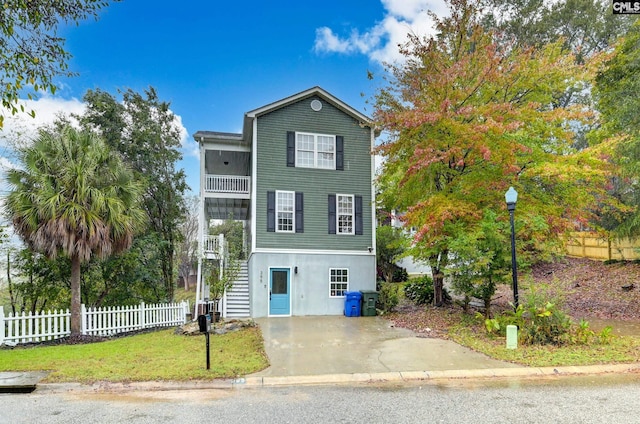 view of front of house featuring a front lawn, stairs, a balcony, and fence