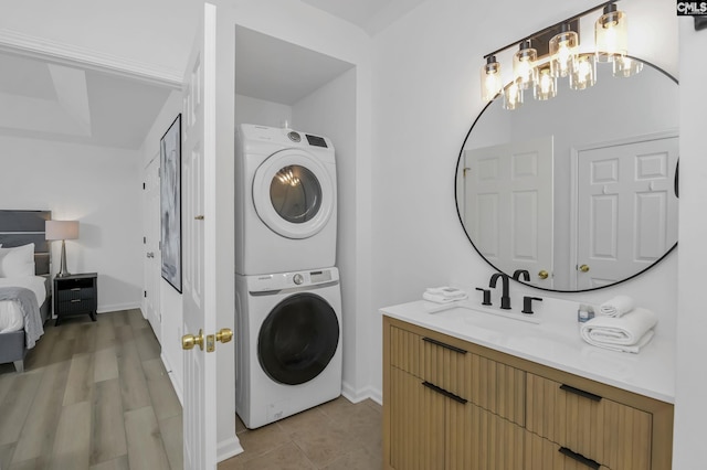 washroom featuring laundry area, stacked washer / drying machine, baseboards, and a sink