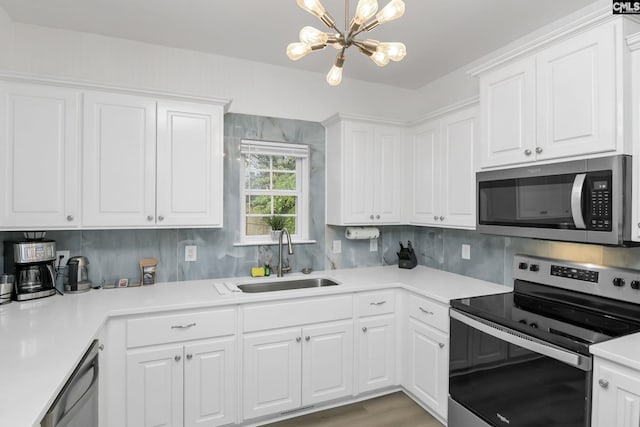 kitchen with a sink, stainless steel appliances, light countertops, white cabinets, and a chandelier