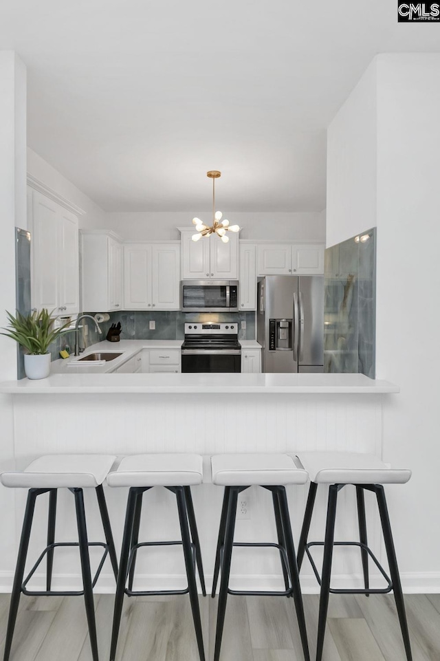 kitchen featuring a sink, light countertops, a peninsula, and stainless steel appliances