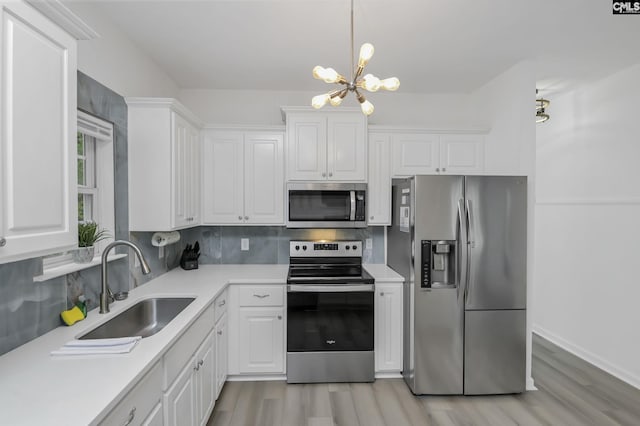 kitchen with a sink, stainless steel appliances, light countertops, white cabinetry, and a notable chandelier