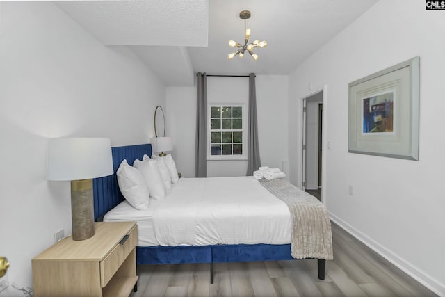 bedroom with baseboards, an inviting chandelier, and wood finished floors