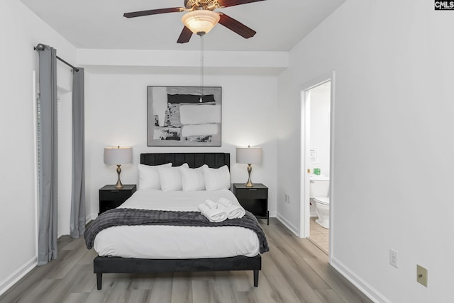 bedroom featuring ensuite bath, light wood-type flooring, baseboards, and a ceiling fan