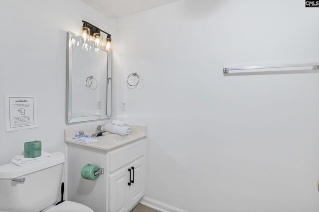 bathroom with toilet, vanity, and baseboards