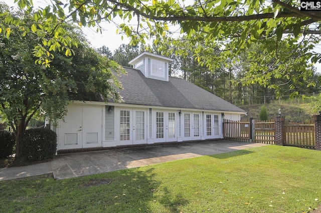 view of front facade featuring a front yard, a patio, fence, roof with shingles, and french doors