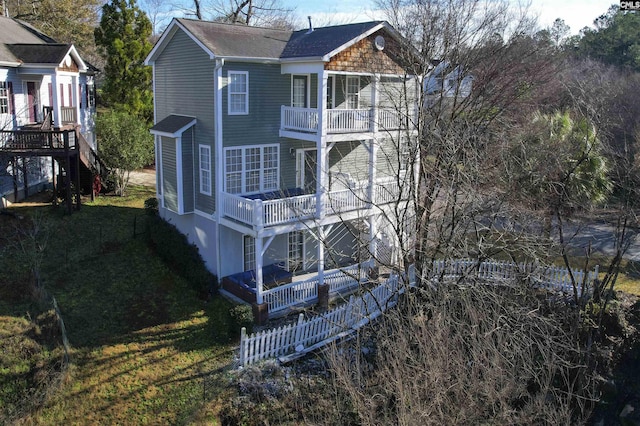 back of house with a balcony and a yard