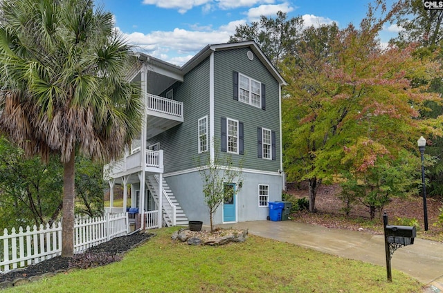 exterior space with stairway, a balcony, fence, stucco siding, and a lawn