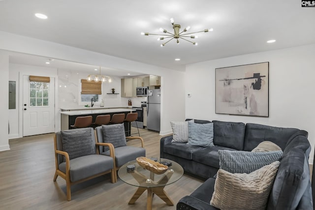 living room featuring baseboards, electric panel, recessed lighting, a notable chandelier, and light wood-type flooring