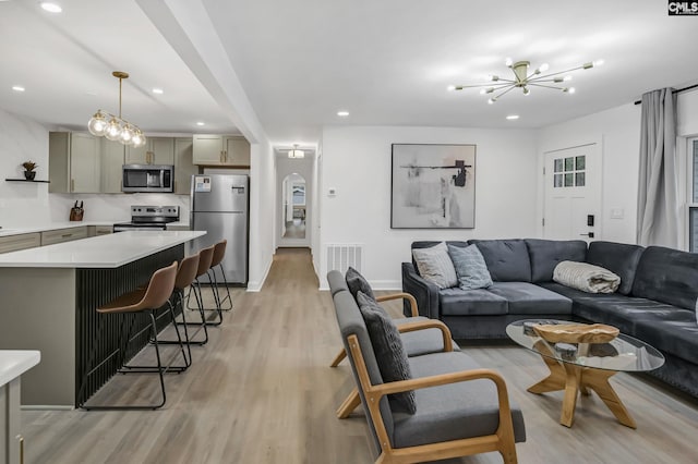 living area with visible vents, recessed lighting, an inviting chandelier, light wood-style floors, and arched walkways