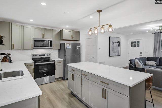 kitchen featuring a sink, stainless steel appliances, gray cabinetry, and open floor plan