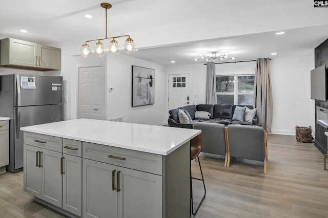 kitchen featuring light countertops, light wood-style floors, freestanding refrigerator, and gray cabinetry