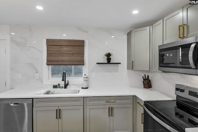 kitchen with gray cabinetry, decorative backsplash, recessed lighting, stainless steel appliances, and a sink