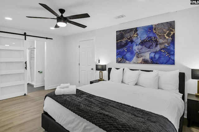 bedroom with visible vents, ceiling fan, a barn door, recessed lighting, and wood finished floors