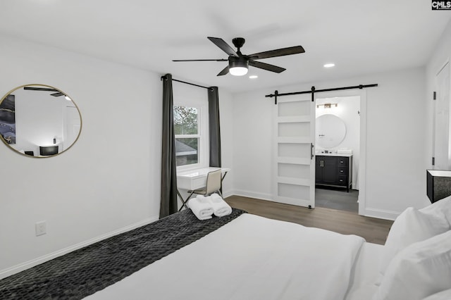 bedroom with recessed lighting, a barn door, baseboards, and wood finished floors