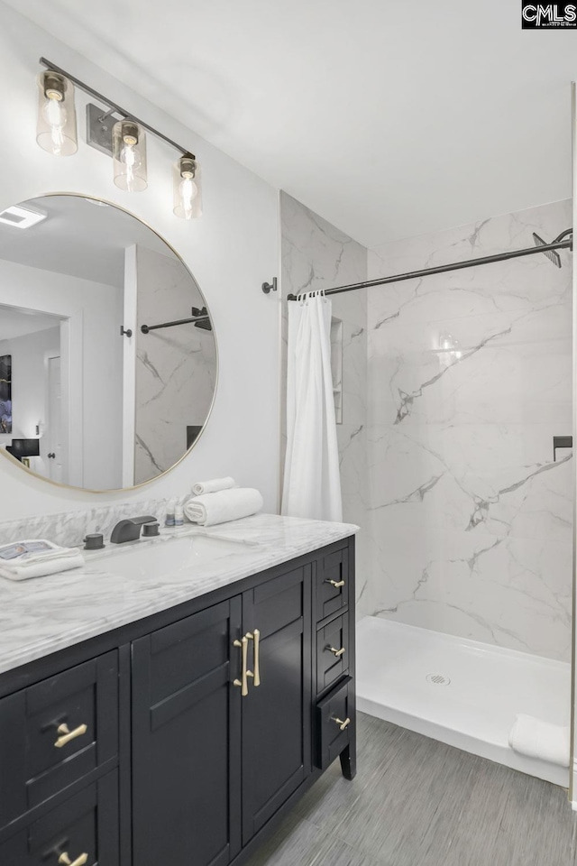 full bath with a marble finish shower, visible vents, and vanity