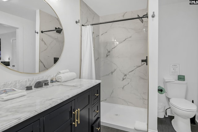 full bathroom featuring a marble finish shower, toilet, and vanity