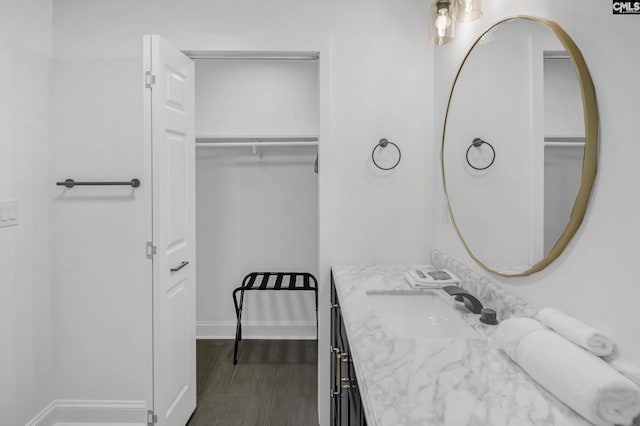 bathroom featuring a spacious closet, vanity, and baseboards