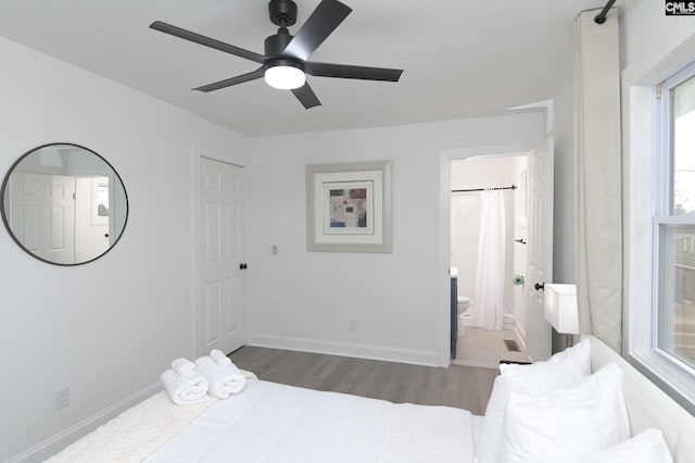 bedroom featuring ensuite bath, wood finished floors, baseboards, and ceiling fan