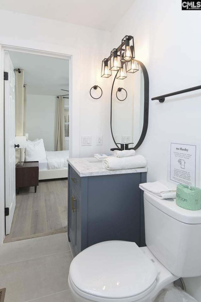 full bath featuring toilet, vanity, and wood finished floors