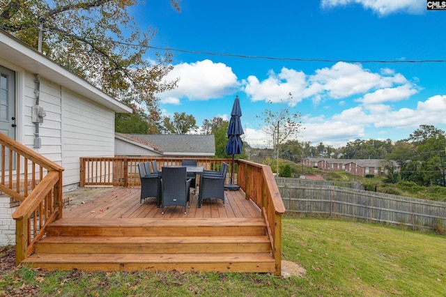 wooden terrace featuring a lawn, outdoor dining space, and fence