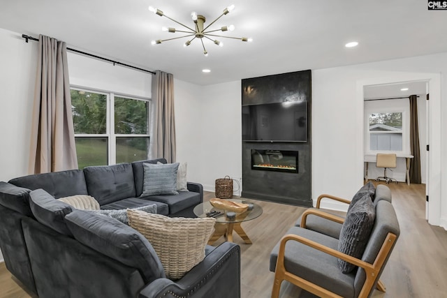 living area featuring light wood-style flooring, recessed lighting, a chandelier, and a large fireplace