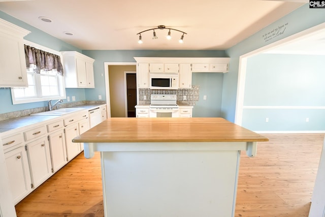 kitchen featuring light wood-type flooring, a sink, a kitchen island, white cabinetry, and white appliances