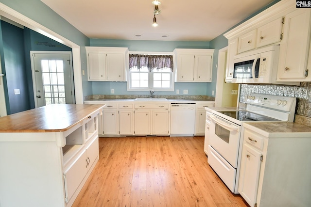 kitchen with light wood-style flooring, white appliances, white cabinets, and a sink