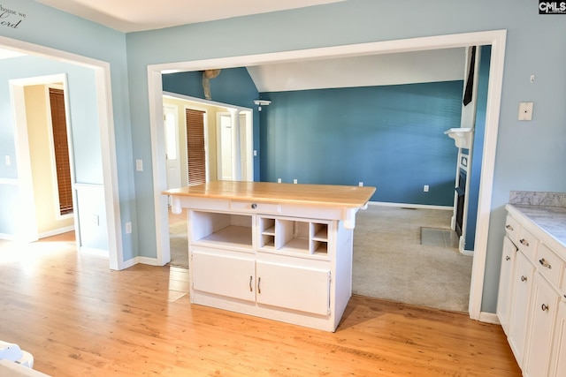 kitchen with white cabinetry, light wood-type flooring, baseboards, and light countertops