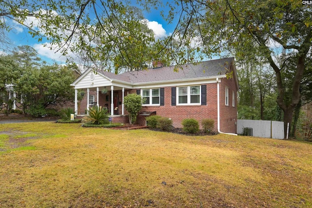 view of front of home with a front lawn, fence, brick siding, and a chimney