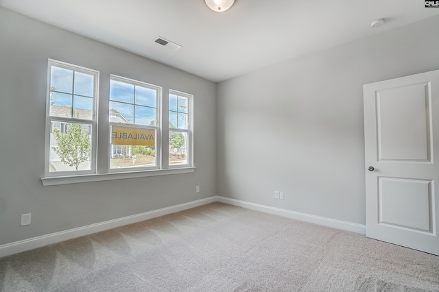 empty room featuring visible vents, baseboards, and light colored carpet