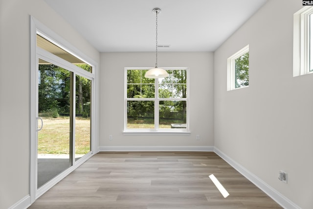 unfurnished dining area with plenty of natural light, visible vents, light wood-style floors, and baseboards