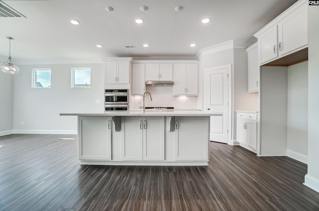 kitchen with tasteful backsplash, light countertops, dark wood-type flooring, and ornamental molding