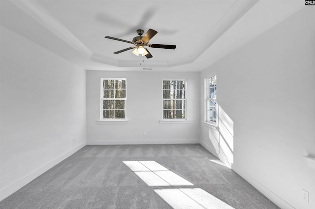 carpeted spare room with a tray ceiling, baseboards, and ceiling fan