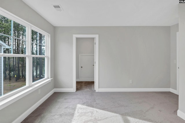 carpeted spare room featuring visible vents, a healthy amount of sunlight, and baseboards