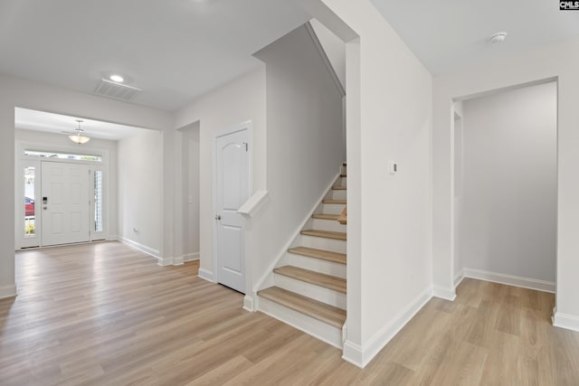 entrance foyer with light wood finished floors, stairway, visible vents, and baseboards