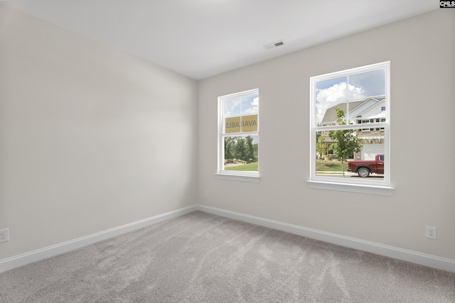 spare room featuring visible vents, baseboards, and light colored carpet