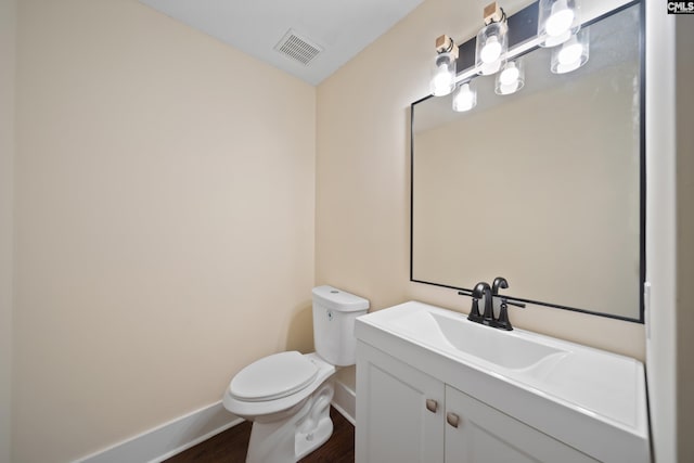 half bath with visible vents, baseboards, toilet, and vanity