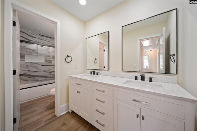 bathroom with double vanity, toilet, wood finished floors, and a sink