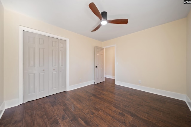 unfurnished bedroom with a closet, a ceiling fan, dark wood-type flooring, and baseboards