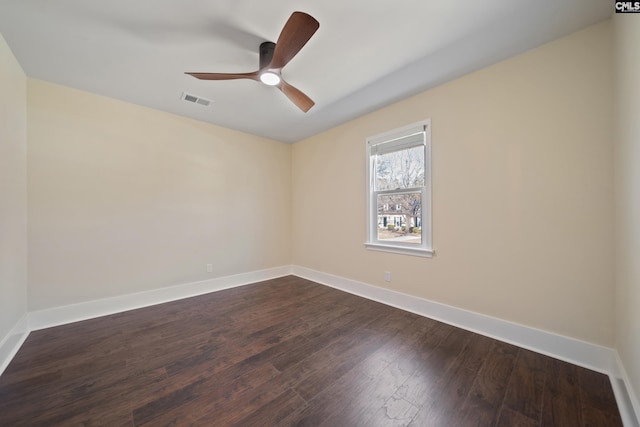 empty room with dark wood finished floors, visible vents, a ceiling fan, and baseboards